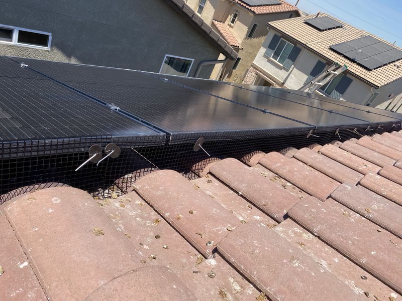 Critter-guard mesh installed around a rooftop solar array on a tile roof